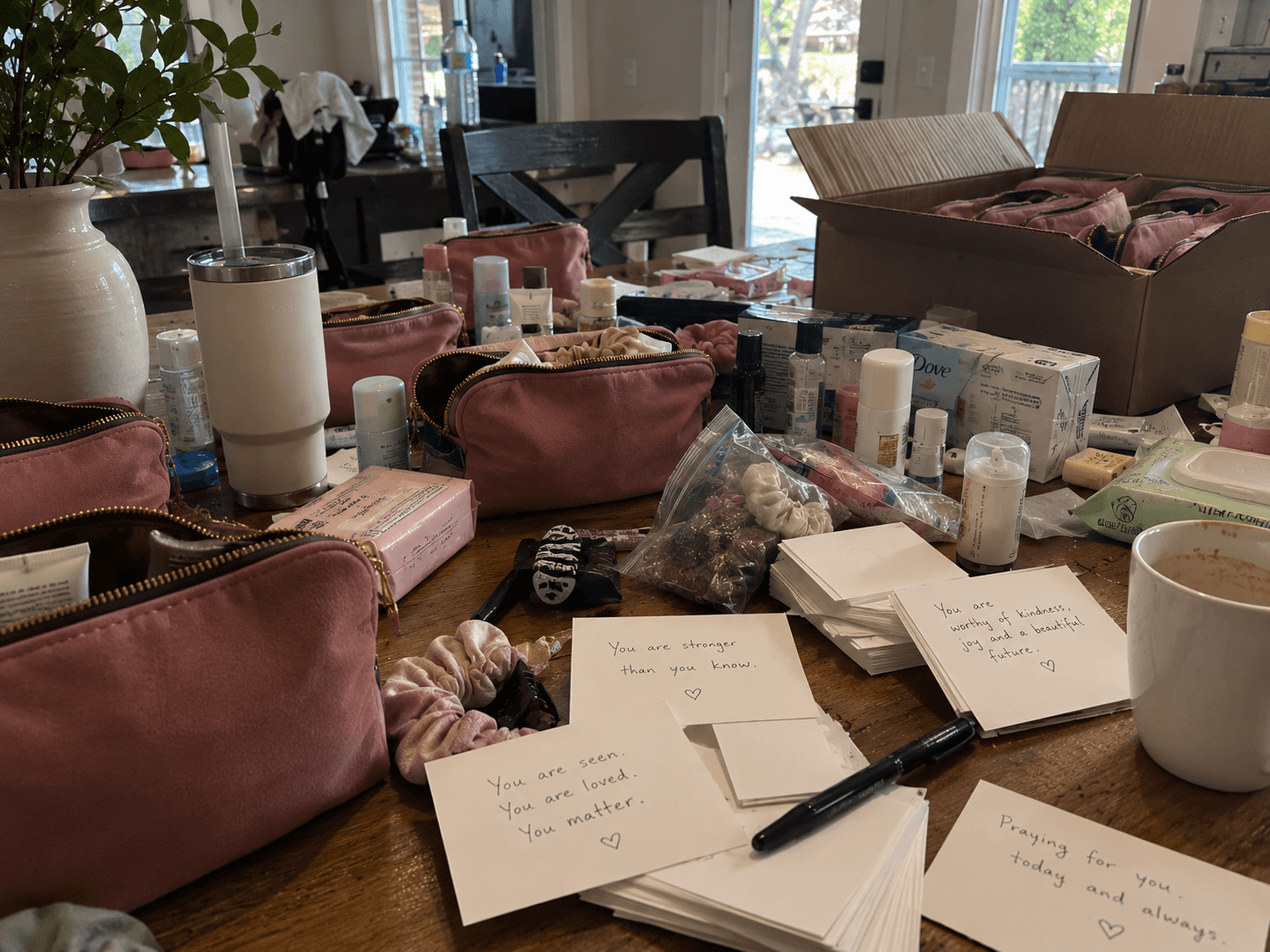 Notes reading You are seen, You are loved, You matter, among gift bags being packed
